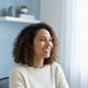 A smiling woman in her 30s in a bright, modern home office, conveying relief and satisfaction.